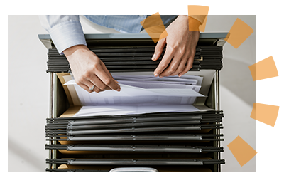 A male business employee placing paperwork inside a green filing folder.