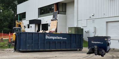 Dumpsters.com Roll Off Dumpster and Front Load Dumpster in Front of Building