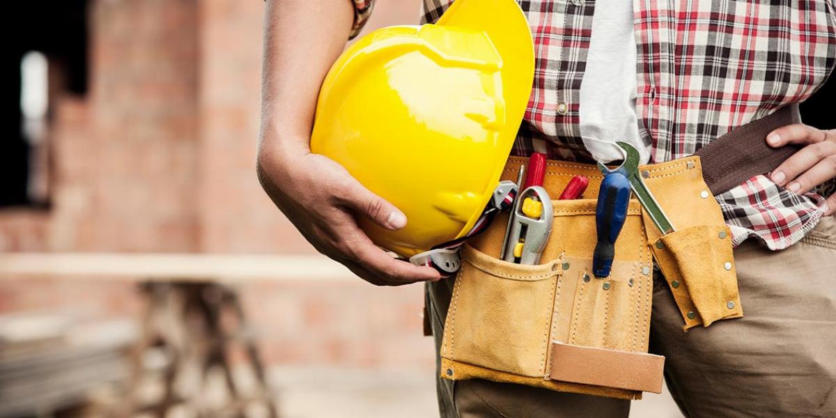 Construction Worker Holding Hard Hat With a Work Belt Around His Waist