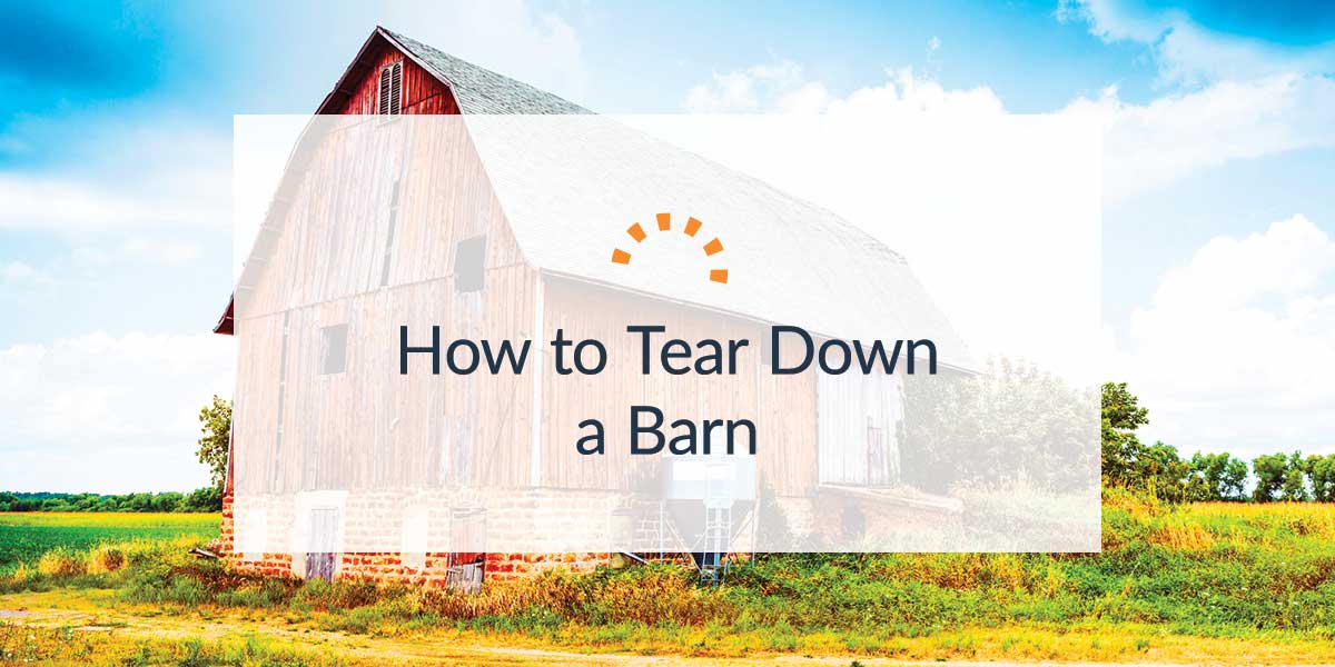 Large red barn in the middle of a field under a blue sky.