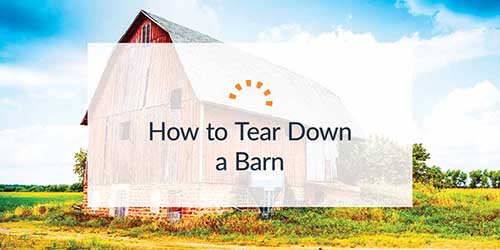 Large red barn in the middle of a field under a blue sky.