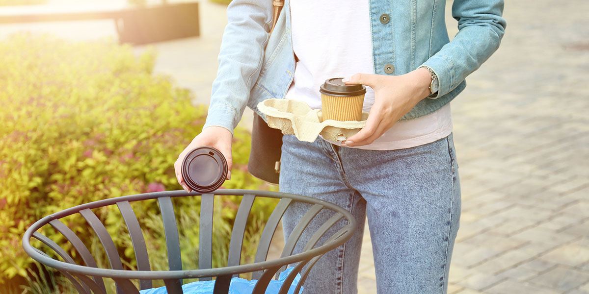 Woman Tossing Coffee Cup in Trash.