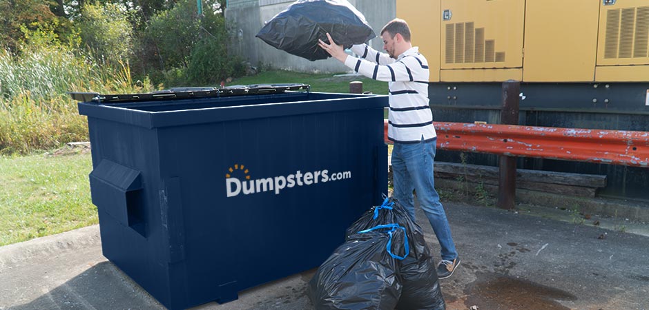 Man wearing a white, striped shirt throwing a bag of garbage into a Dumpsters.com dark blue front load dumpster.