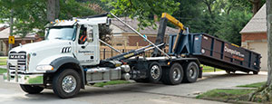 Truck Picking Up a Dumpster from a Driveway