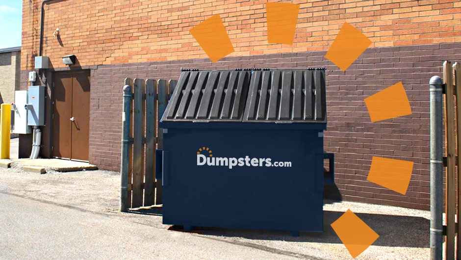 A dark blue Dumpsters.com front load dumpster inside a dumpster enclosure behind a brick building.