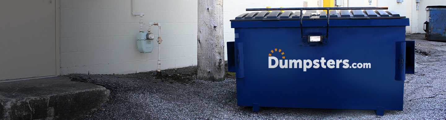 4 Yard Dumpster With Dumpsters.com Logo in Parking Lot in Front of Fence