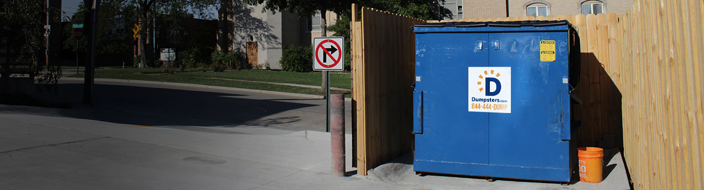 Commercial dumpster in an enclosure.