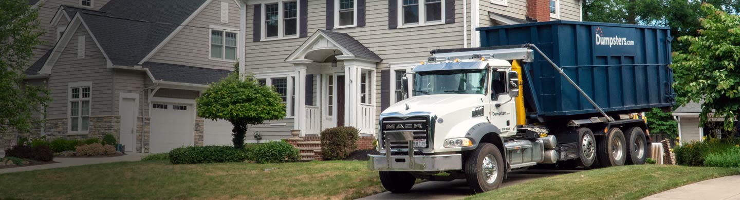 Truck Delivering a Dumpster to a Residential Driveway