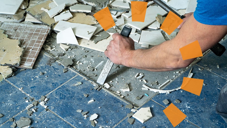A worker scraping tiles off the floor.