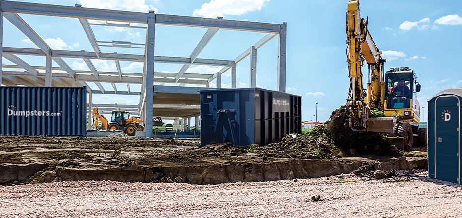 A Dumpsters.com dumpster, storage container, and portable toilet on a jobsite.