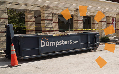 Dumpsters.com roll off dumpster filled with debris in front of a building