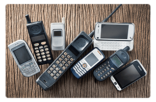 A pile of old cell phones on a table.
