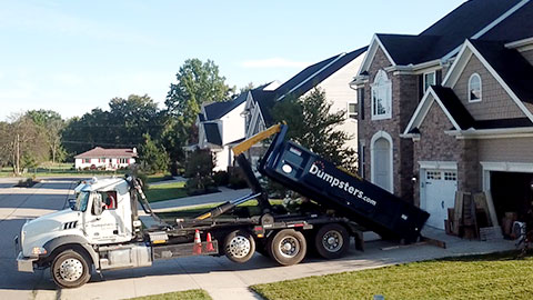 Truck Unloading a Blue Home Dumpster onto a Residential Driveway