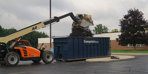 Dumpsters.com blue roll off dumpster being loaded with a small crane.
