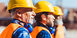 Three Construction Workers Wearing Yellow Hard Hats.