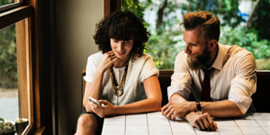 Man and Woman Sitting Next to Each Other Looking at a Phone